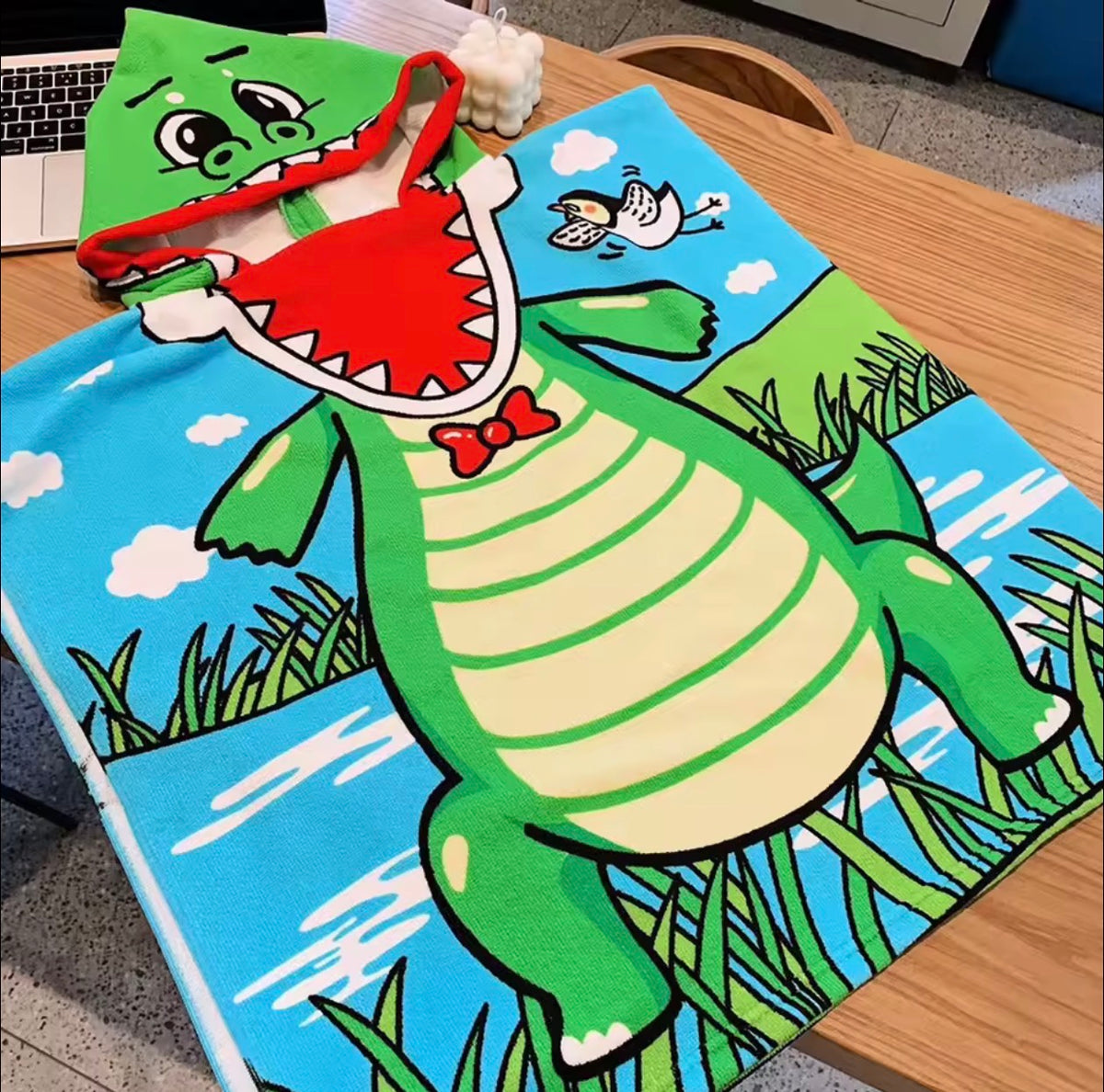 Hooded crocodile poncho towel, laid out on a table